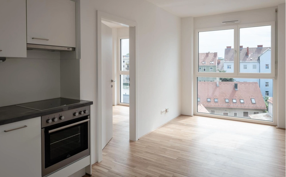 Blick auf einen Teil der Küche mit großem bodentiefem Fenster und Tür zu einem weiteren Zimmer, Karlauerstraße.